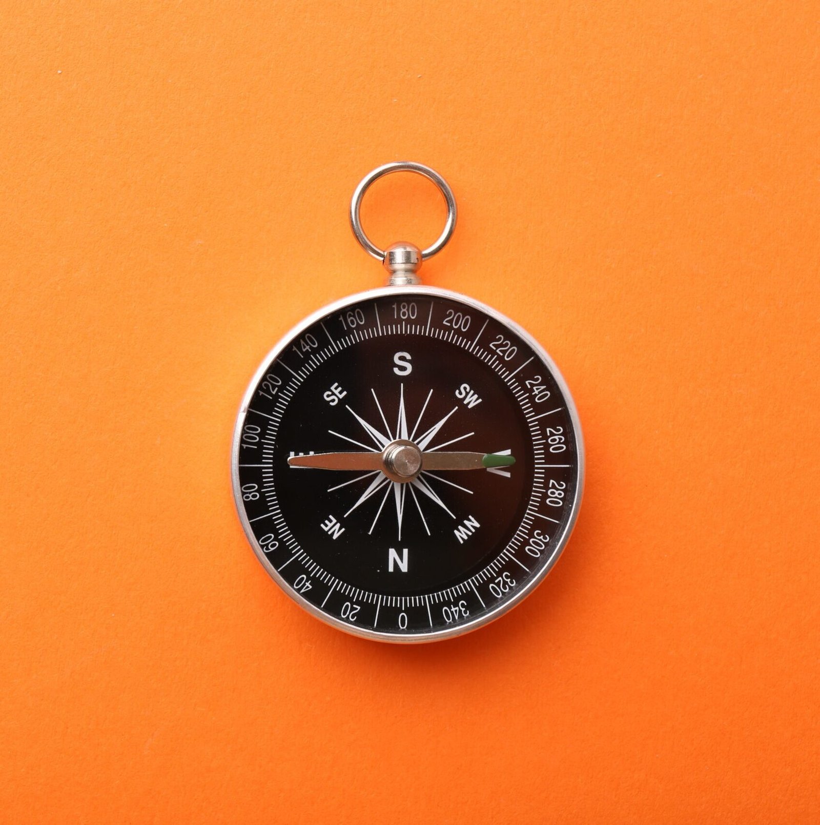 One compass on orange background, top view. Space for text